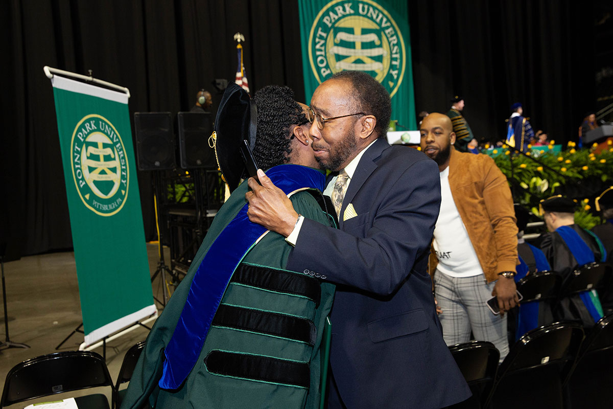 A graduate is embraced by a family member