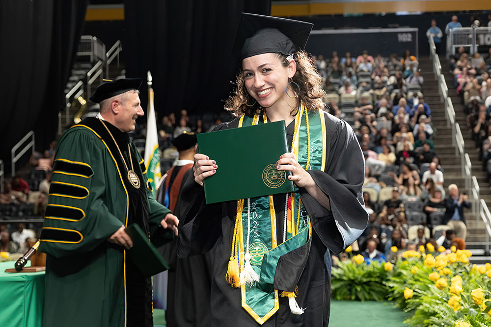 A student cheers as she walks across the graduation stage.