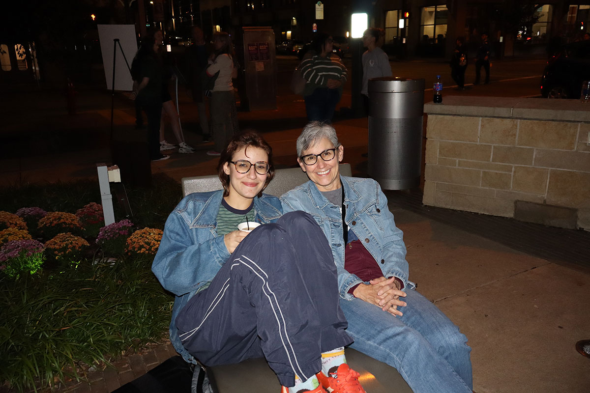 A student and family member sit on a chair in Village Park.