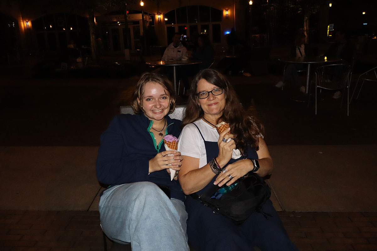 A student and family member sit on a chair in Village Park.
