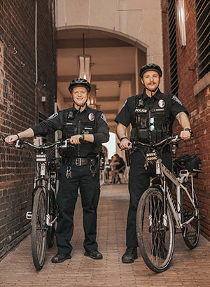 Two officers posed with bicycles near Village Park