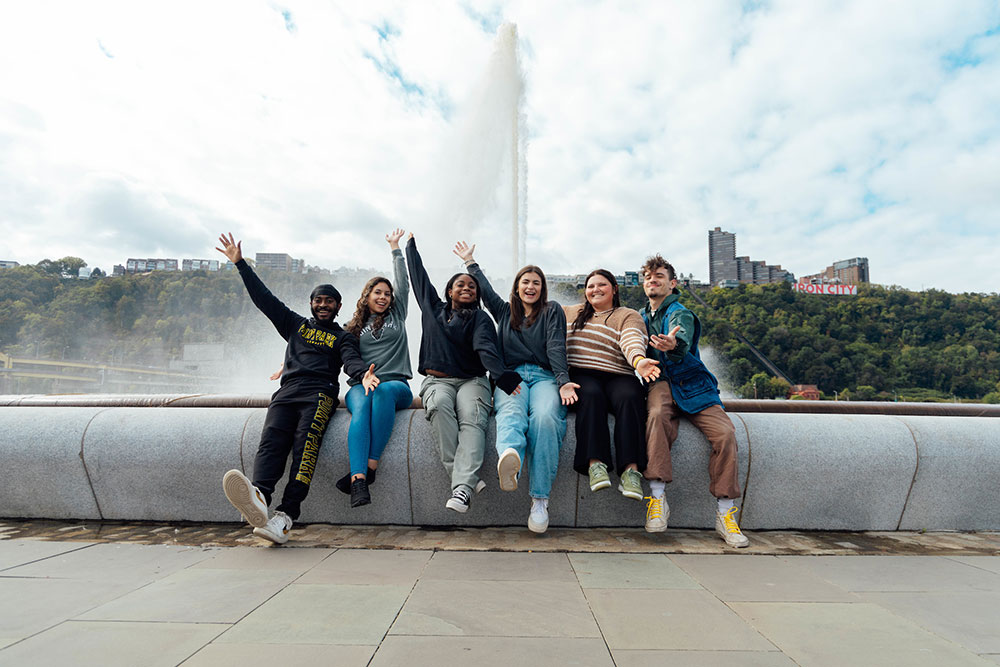 Students sit on the edge of the fountain at Point State Park. 