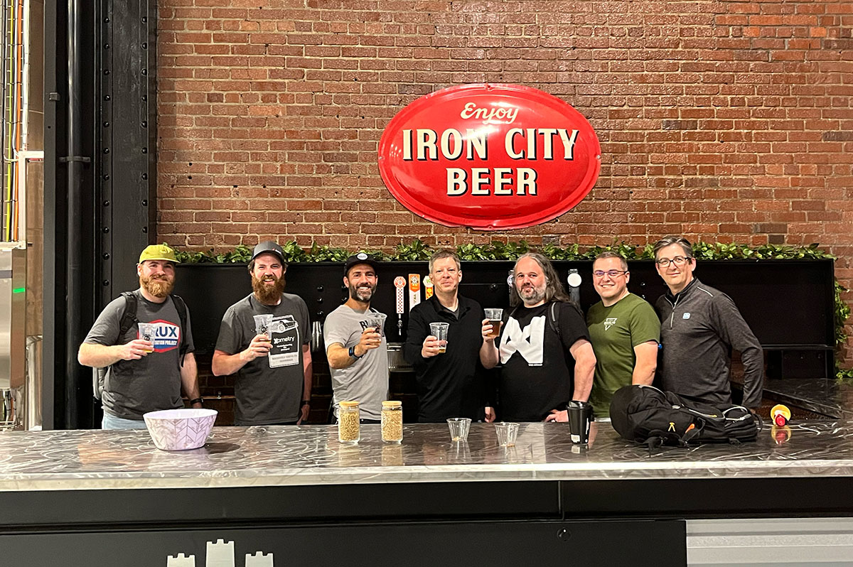 A row of men hold beer glasses up in the air.