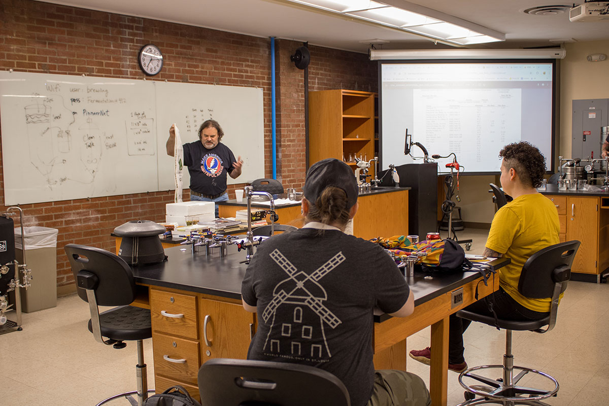 A man teaches a class before a whiteboard.