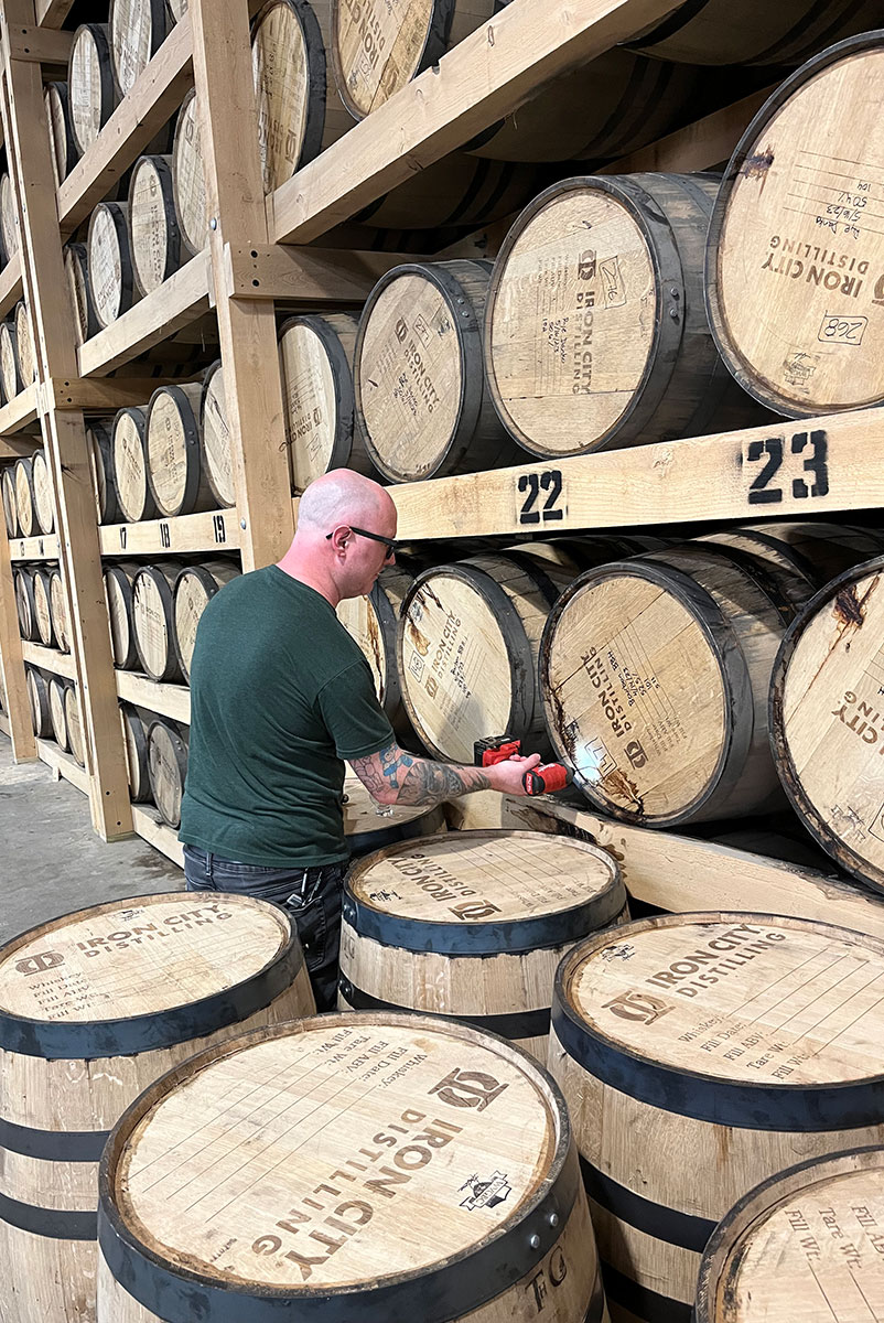 A man drills into a whiskey barrel.