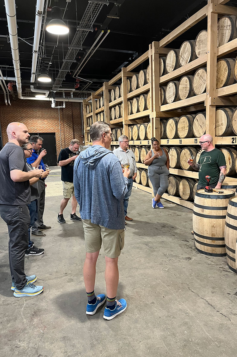 People stand in a room of whiskey barrels.