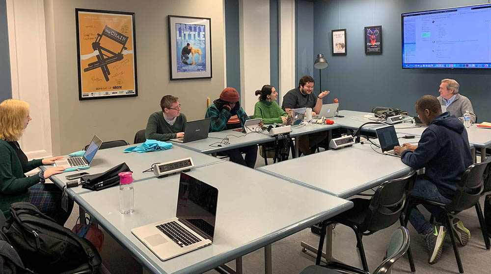 A photo of students and faculty in the writer's room on campus.