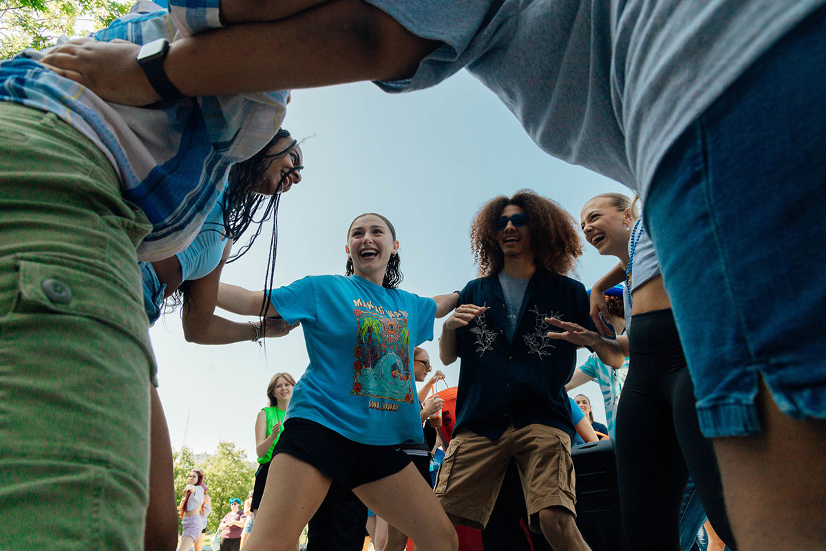 Students link arms for a game in a field.