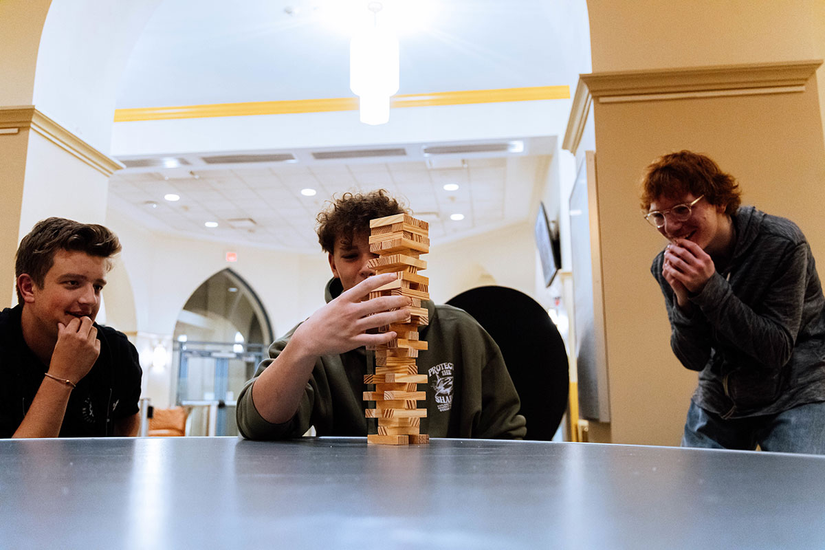 Three students play Jenga.