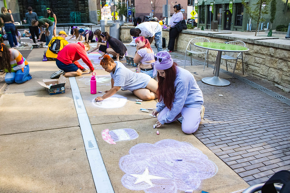 Students color on the sidewalk with chalk