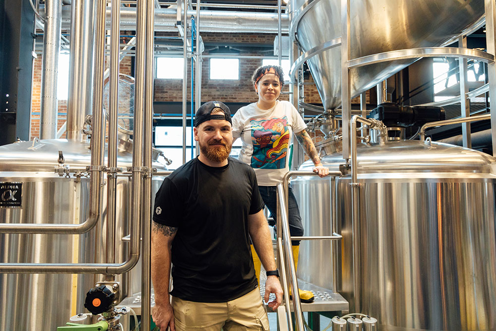 A man and a woman pose in a brewery.