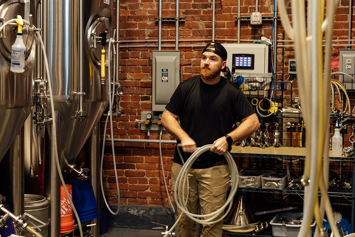 A man holds tubes in a brewery.