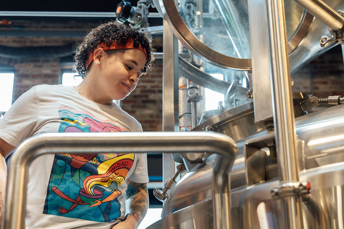 A woman smiles as she works in a brewery.