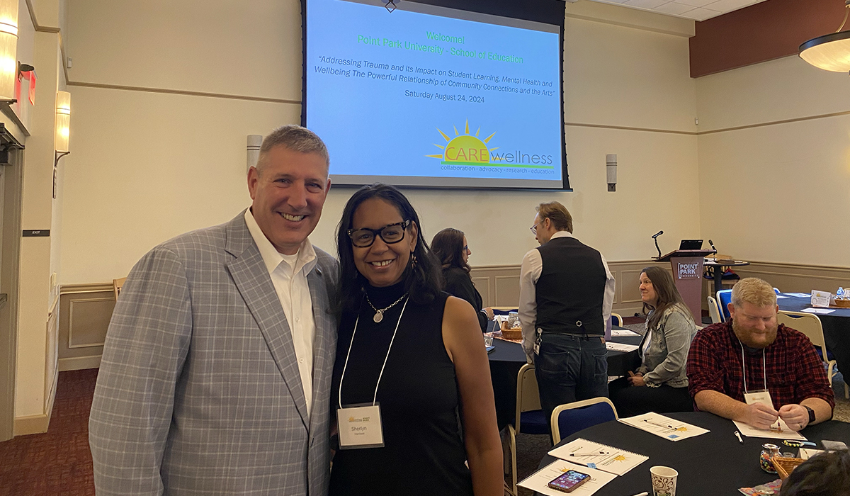 Point Park University President Chris Brussalis and alumna Sherlyn Harrison pose for a photo at the symposium.