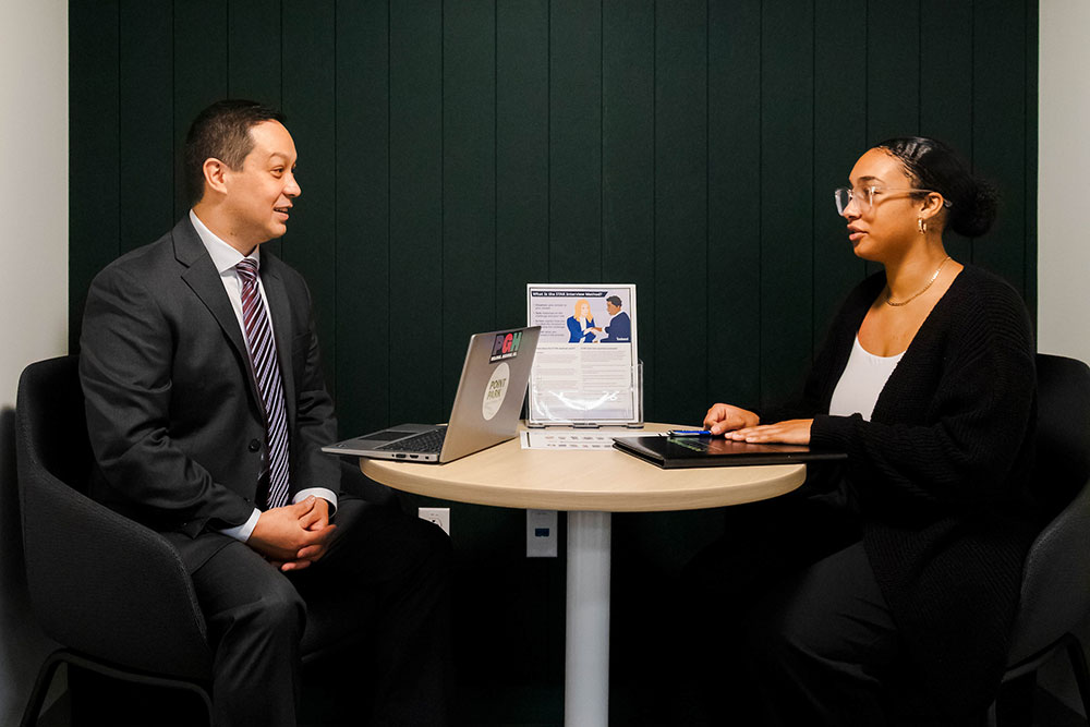 A student and a counselor in the PCRC talk at a table.