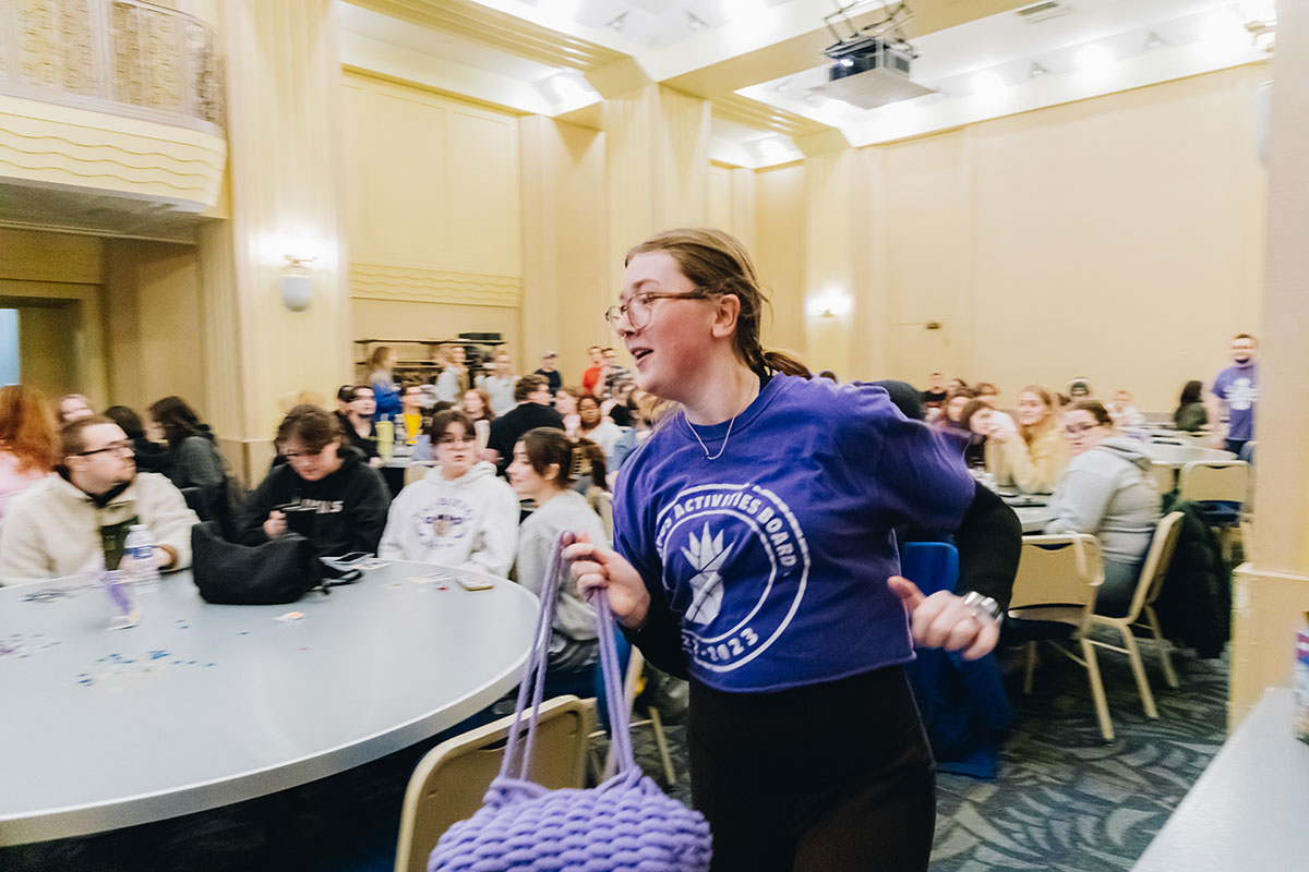 A girl in a purple shirt carrying a purple bag runs. 