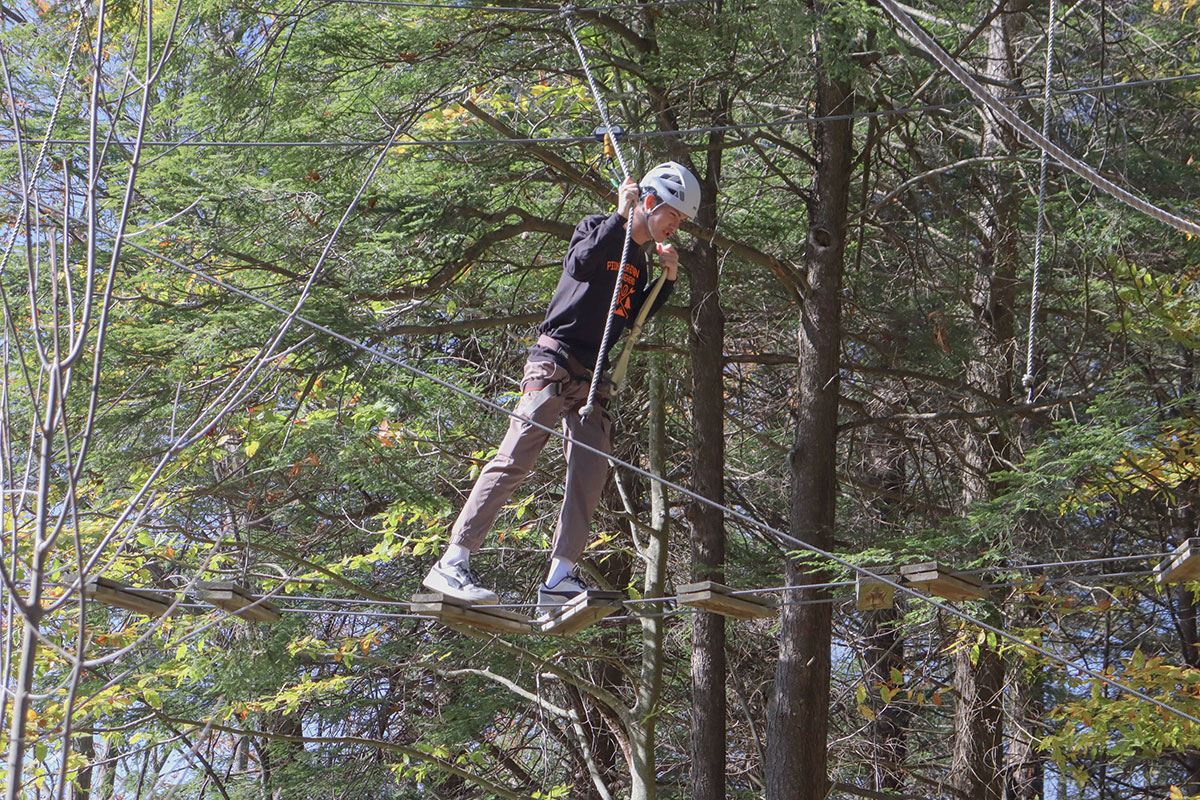 A student navigates a high ropes course.