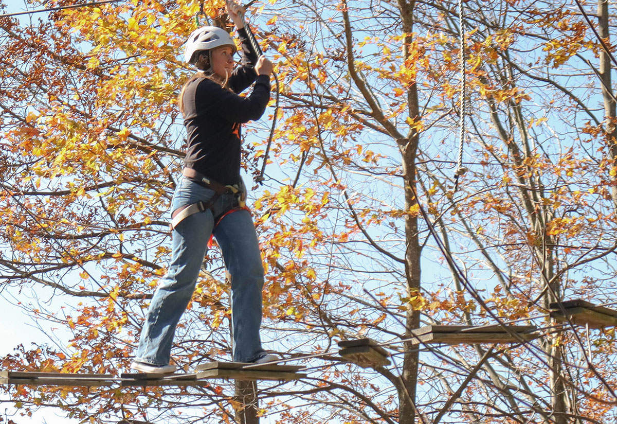 A student navigates a high ropes course.