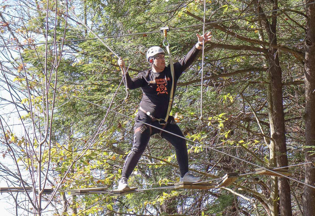 A student navigates a high ropes course.