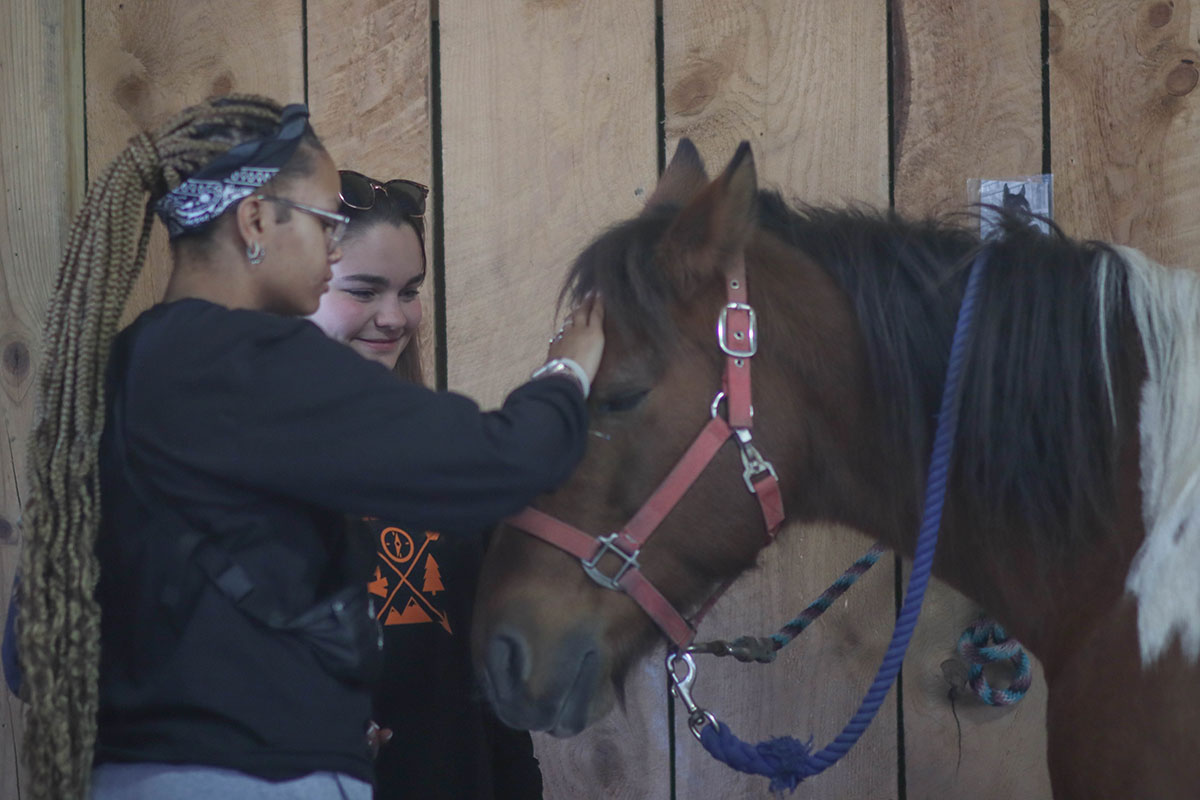 Two students pet a horse.