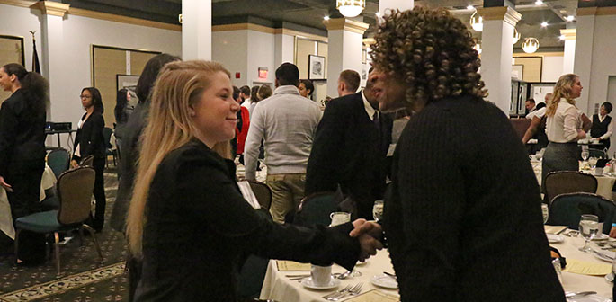 Two women smile and shake hands at Point Park University's annual Networking Reception and Etiquette Dinner 2015. | Photo by Victoria A. Mikula