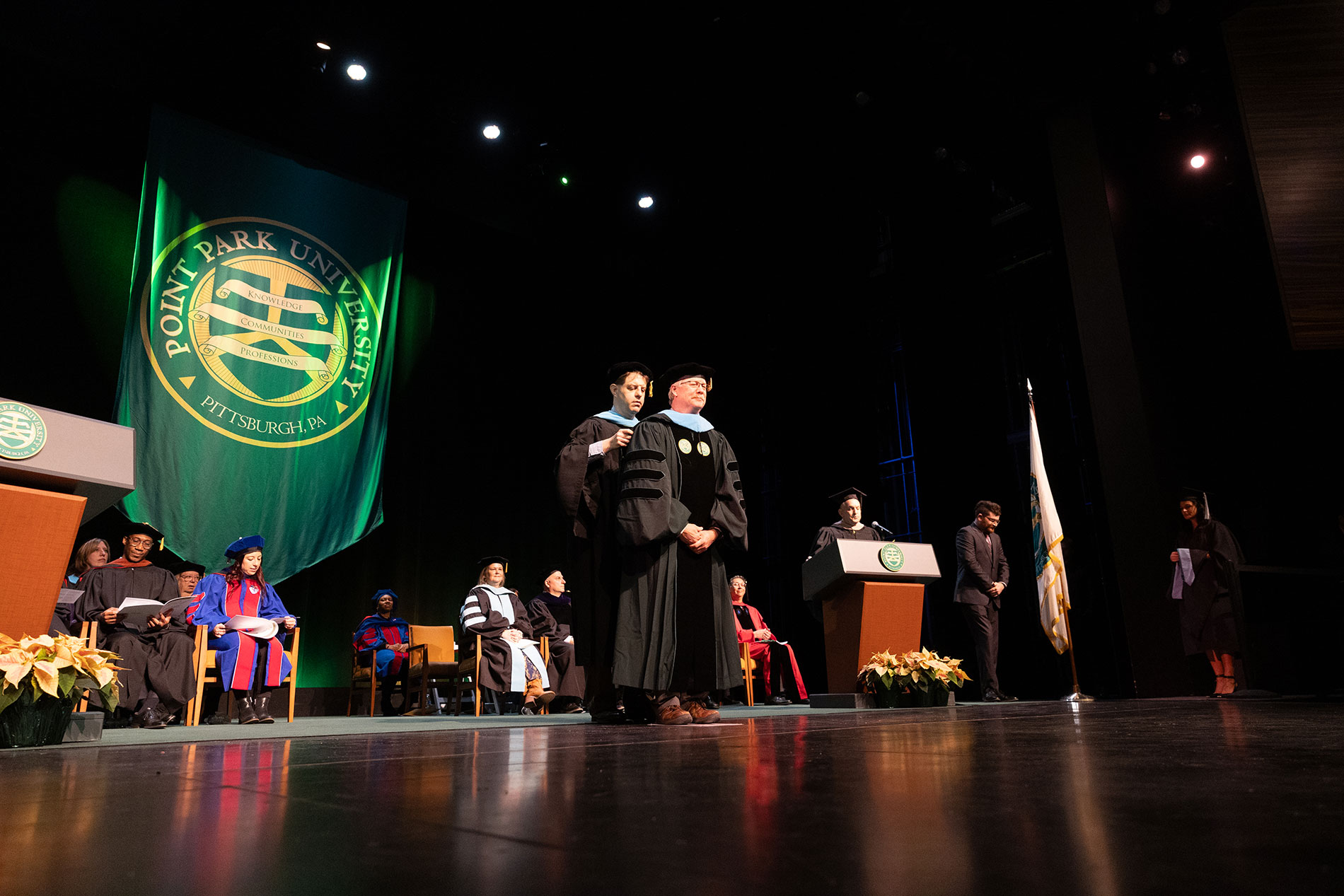 A doctoral student receives their hood on stage.