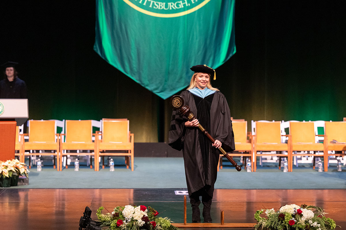 Virginia Chambers stands on the stage with the mace.