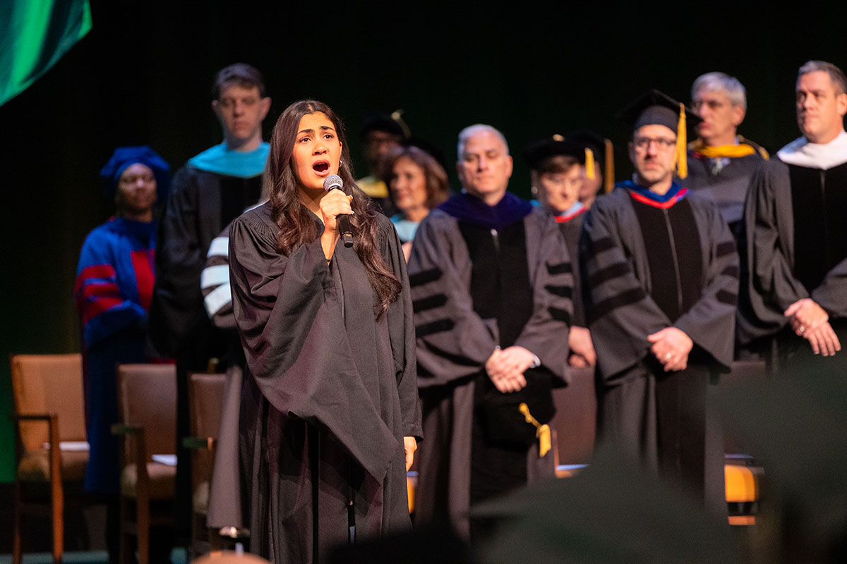 A student sings the national anthem on stage.