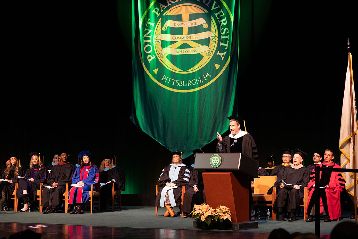 Greg Behr, keynote speaker, stands at a podium.. 