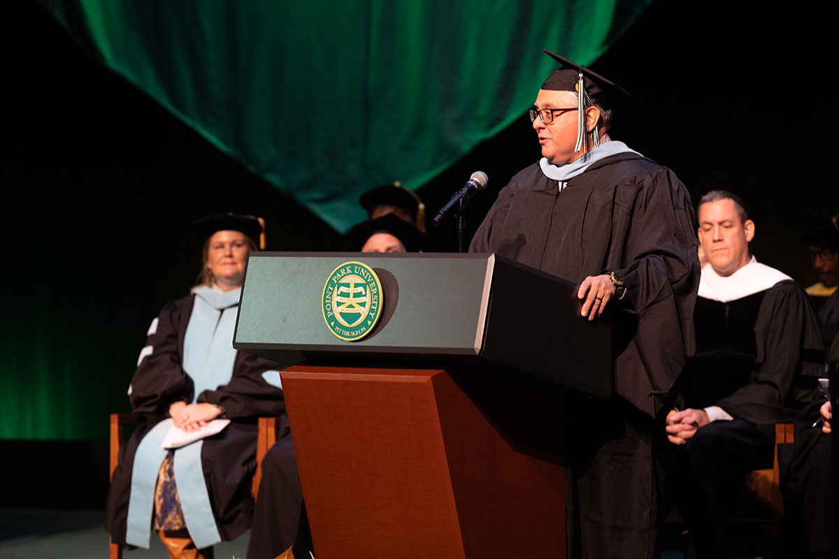 The student speaker stands at the podium. 