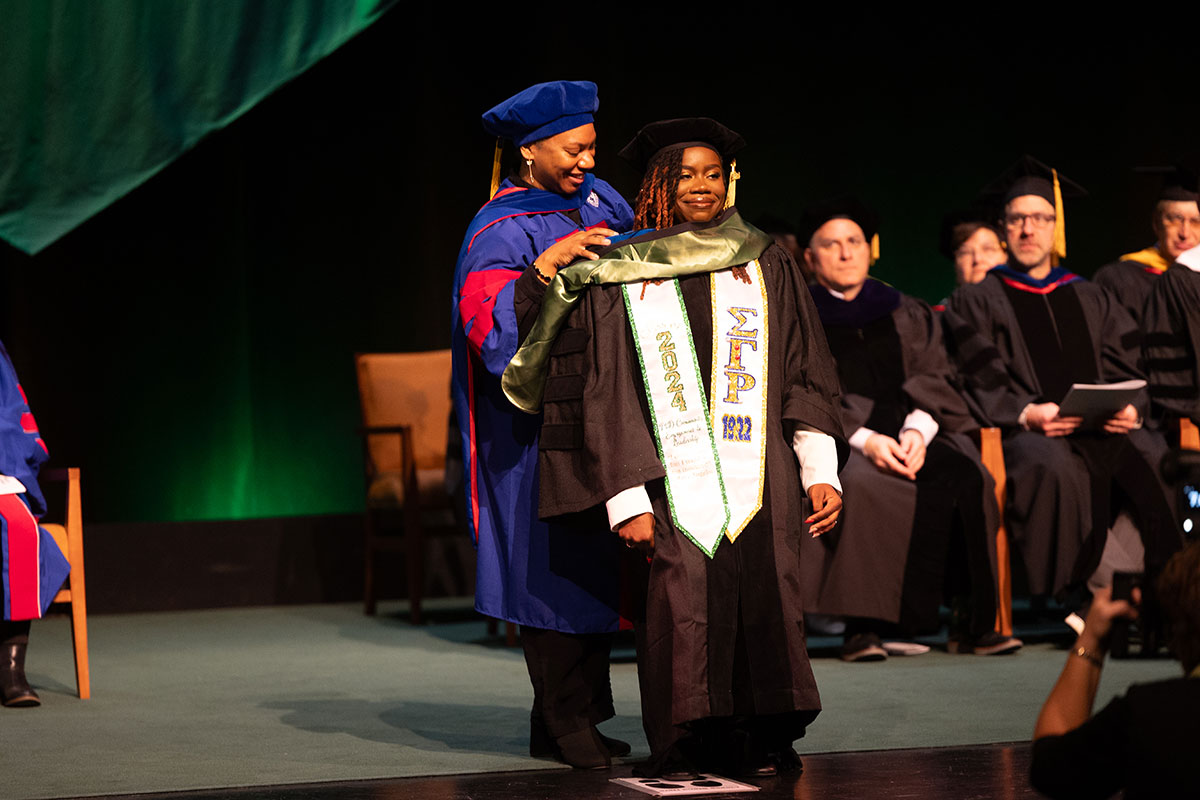 A woman is given her hood on stage. 