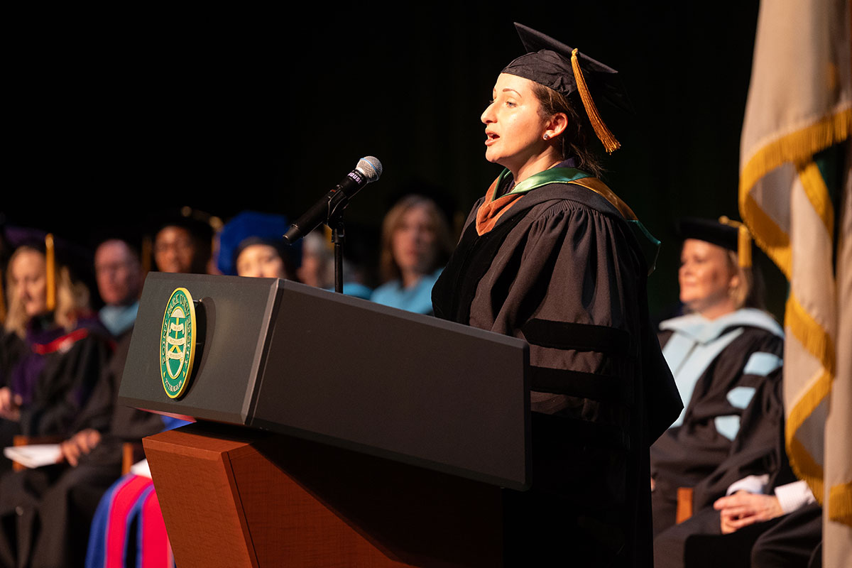 A member of the alumni board stands at the podium. 