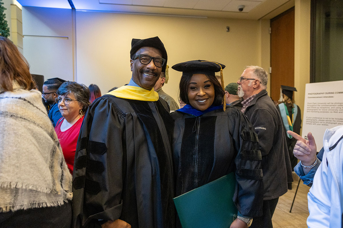 A professor poses for a photo with a graduate. 