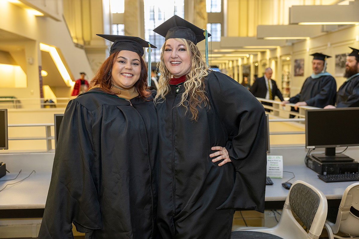 Two graduates pose for a photo. 