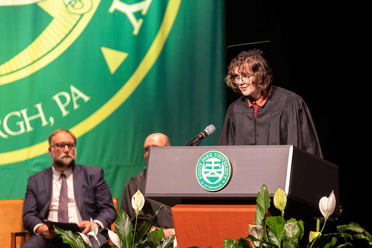 A student in regalia stands at a podium.