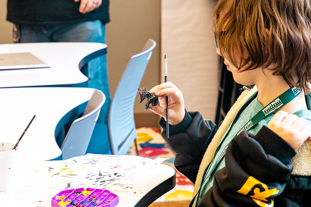 Pictured is Aiden Winward-Green painting a miniature. Photo by Ethan Stoner.