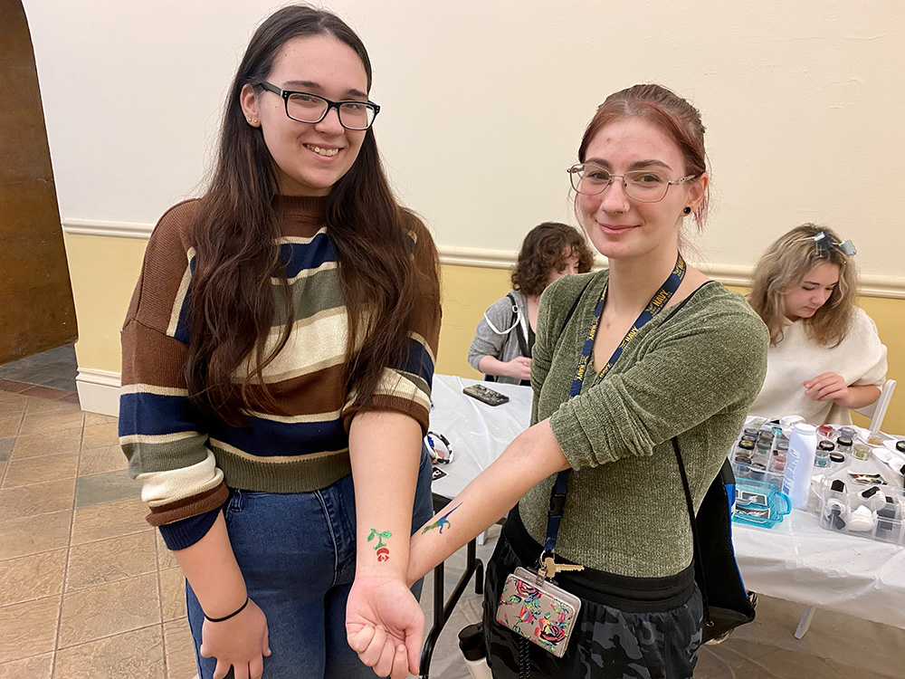 Two students pose with glitter tattoos at the Pioneer Pause.