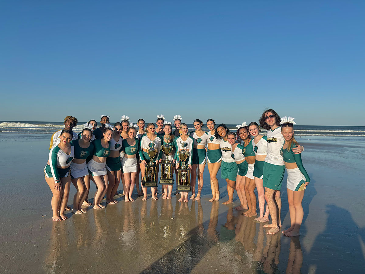 Cheer and dance team stands on a beach.