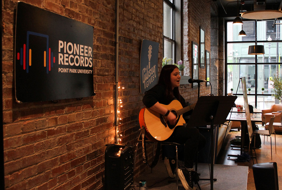 A student plays guitar in Point Perk.