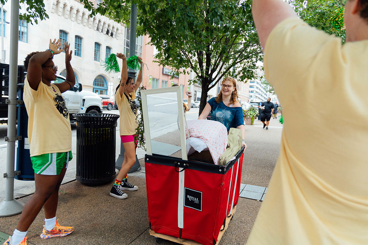 New Students walk with red bins full of items.