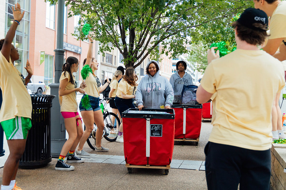 New Students walk with red bins full of items.